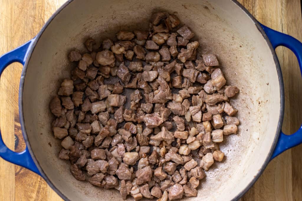 Browning the diced lamb in a Dutch oven.