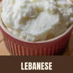 Whipped white toum garlic sauce in a red ramekin on a wooden board.