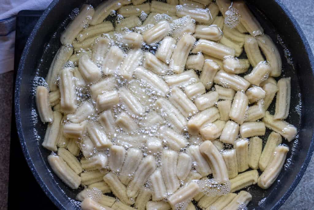 Piped dough pieces started to cook in oil.