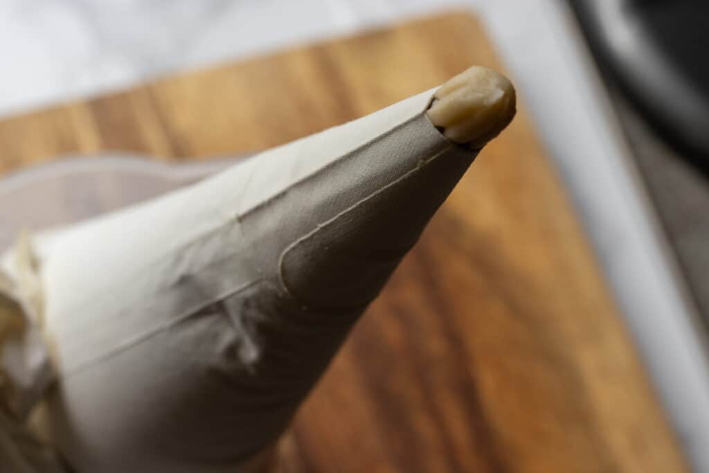 Tulumba dough is transferred to a piping bag with a star nozzle.
