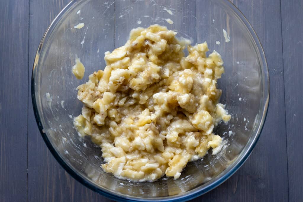 Ripe bananas are mashed in a bowl.
