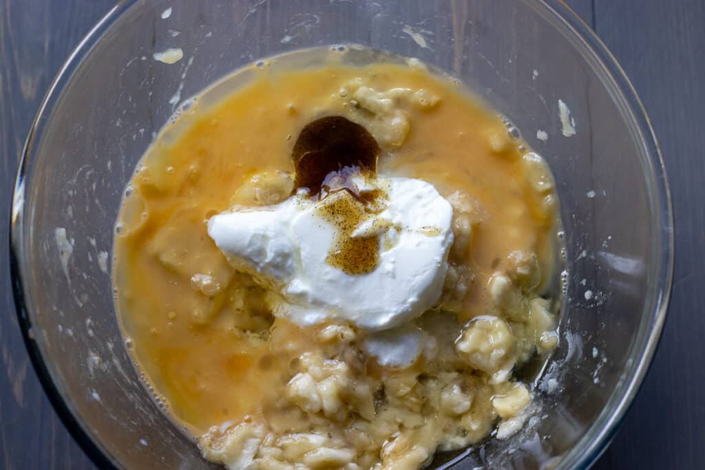 Yogurt, egg, vanilla, and sugar are added to mashed bananas.
