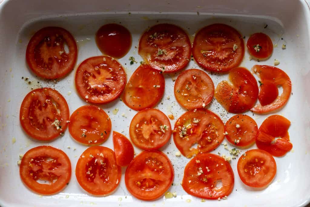 Sliced tomatoes layered on a bottom of baking dish.