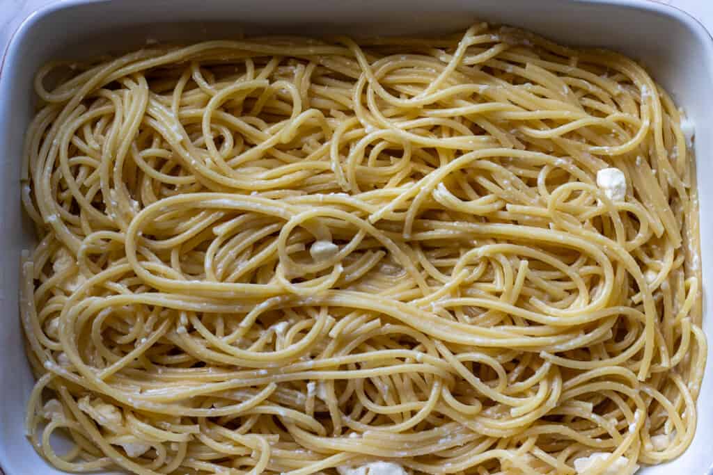 Cooked pasta layered in a baking dish.