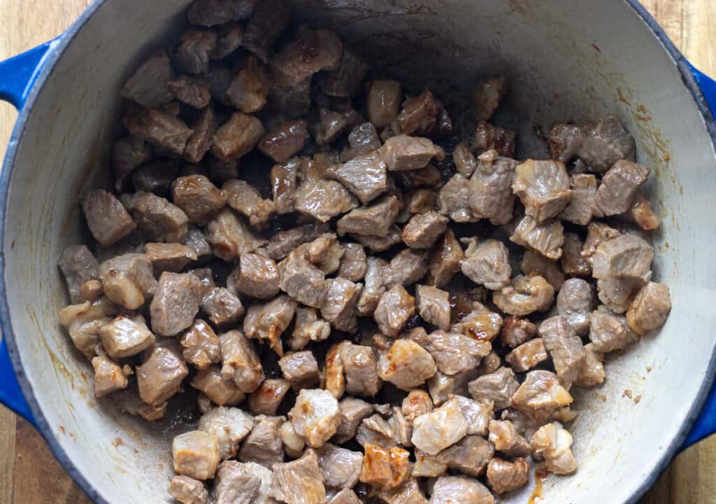 Browning the diced lamb in a Dutch oven.