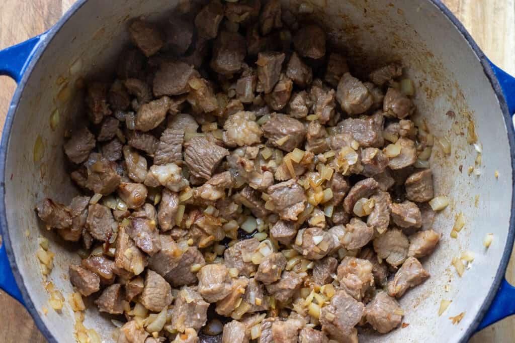 Sauteing the onions and garlic with the browned lamb.