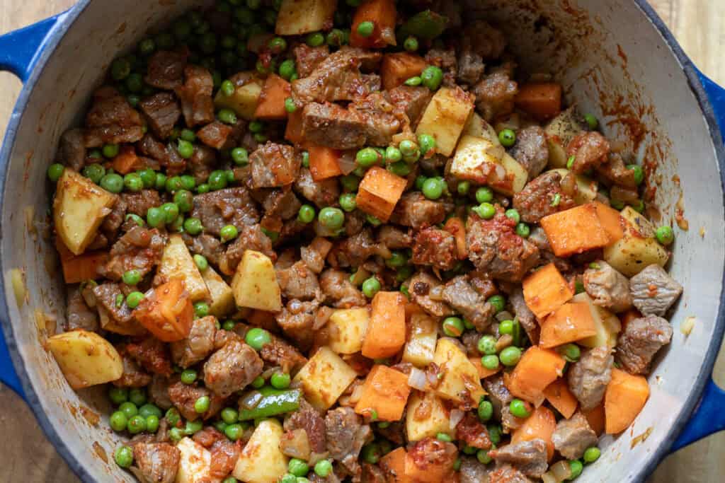 Meat and vegetables stirred together with the tomato paste.