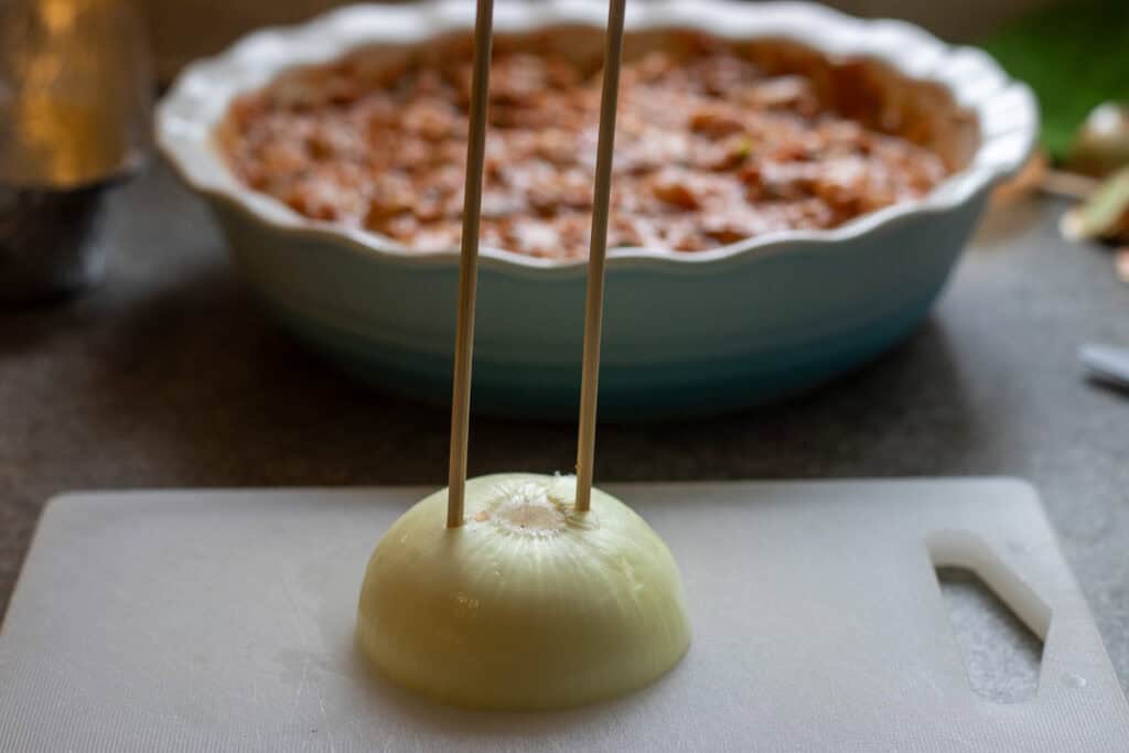 Two bamboo skewers pushed into a half onion.