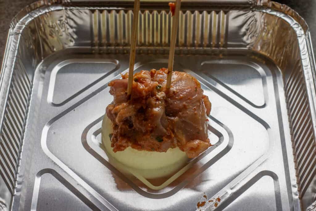 Threading marinated chicken thighs onto the skewers.