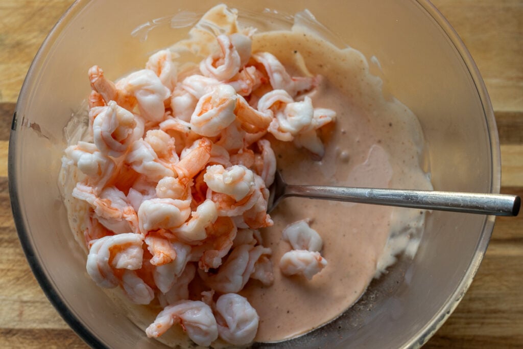 Shrimp are tossed in cocktail sauce.