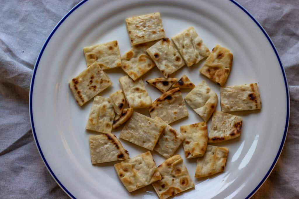Lightly toasted pita bread pieces are arranged on a plate.