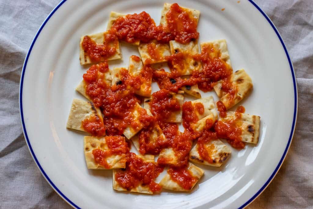 Tomato sauce is poured over toasted pita bread pieces.