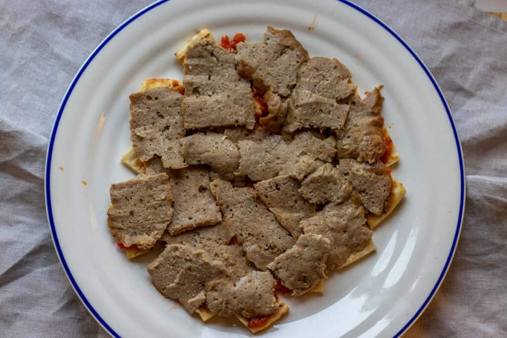 Sliced doner meat is placed on top of pita bread.