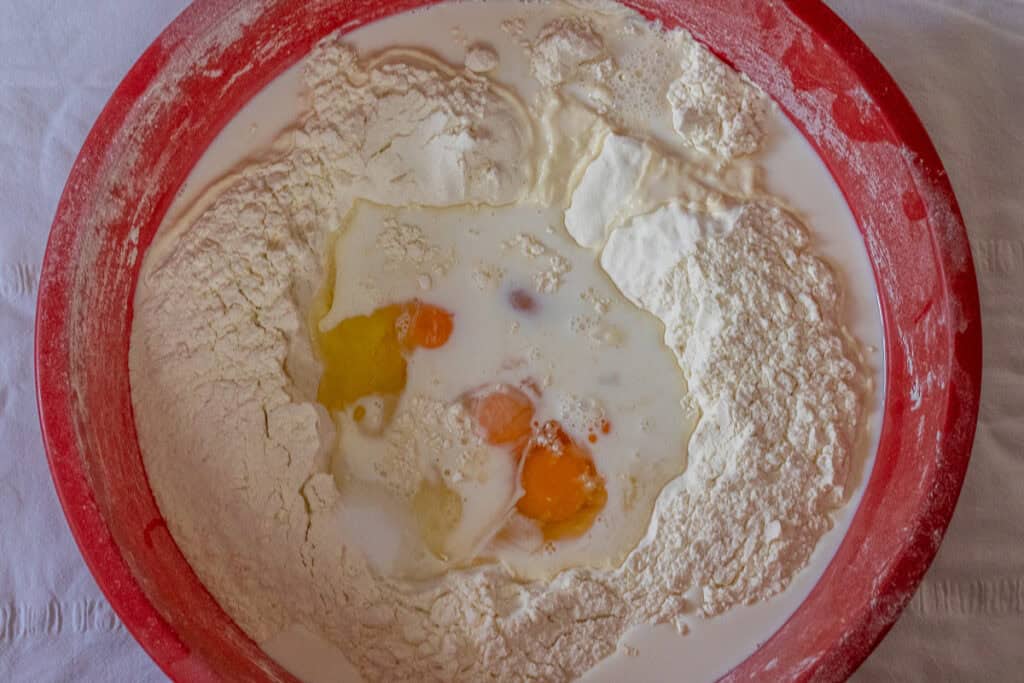 Flour, eggs, milk, water, and salt placed in a large bowl.