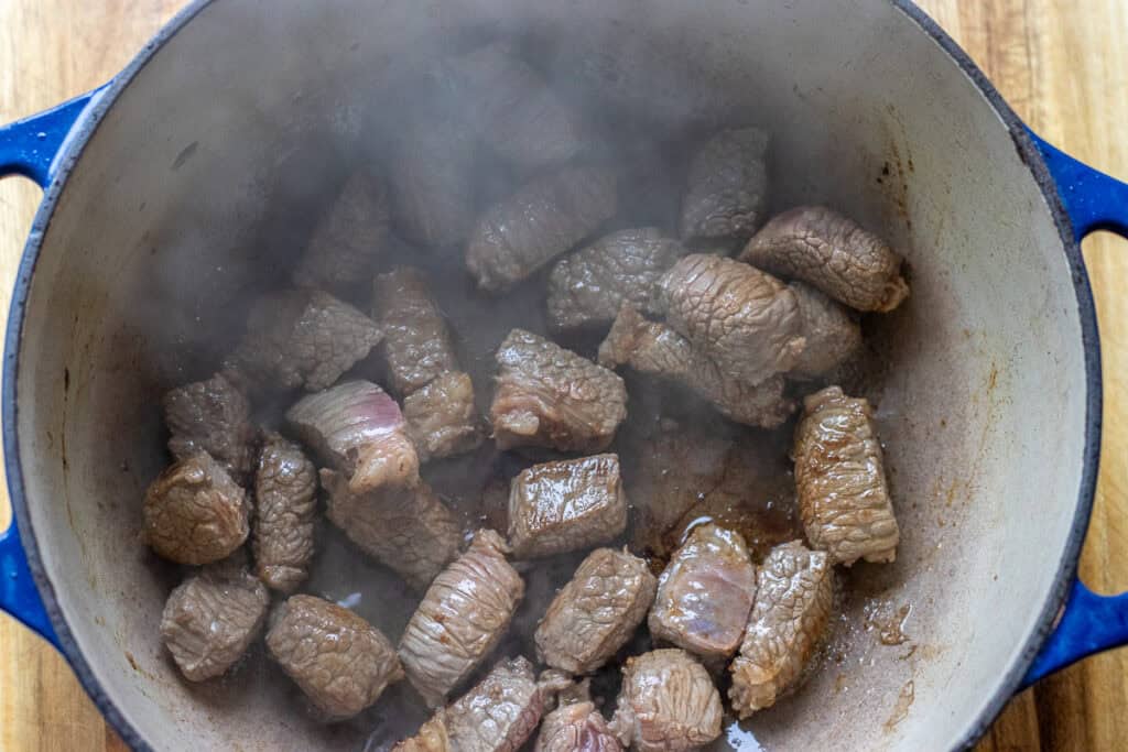 Searing the beef with olive oil in a Dutch oven.