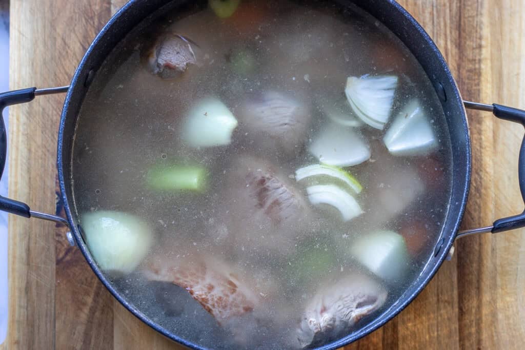 Carrots, celery, onions, garlic, and water are added to the lamb.