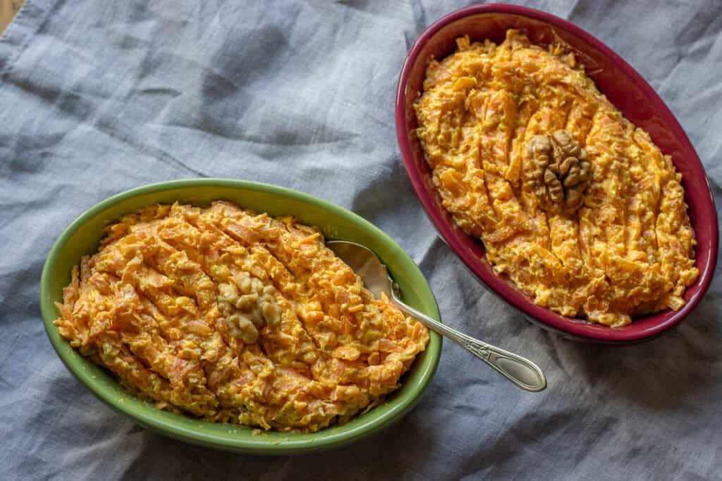 Two dishes of carrot dip with yogurt, each topped with a walnut half.