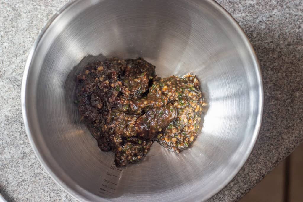 The blended walnut and pomegranate molasses paste in a steel mixing bowl.