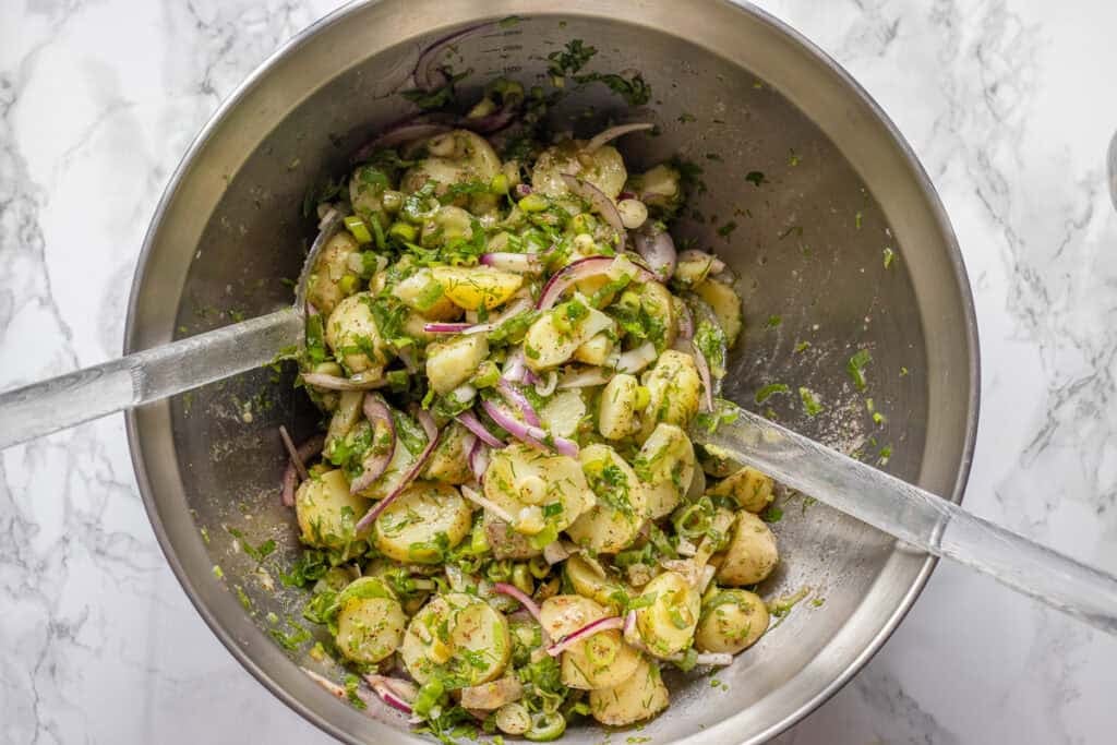 Potato salad ingredients tossed together in a bowl.