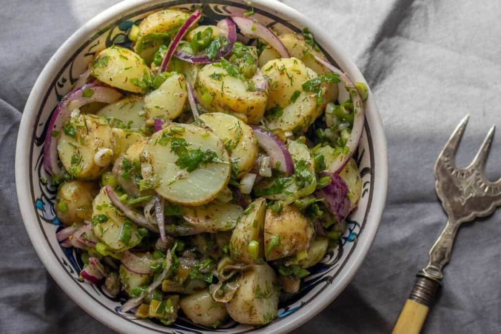 Turkish potato salad served in a patterned bowl with a serving fork.