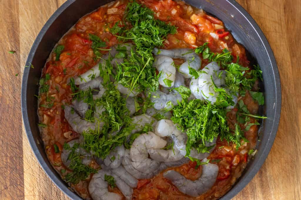 Raw shrimp and fresh herbs are added to tomato sauce.