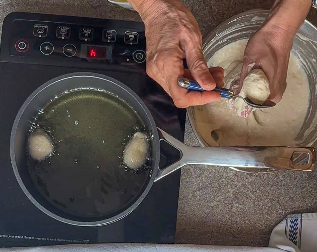 scooping lokma dough into hot oil