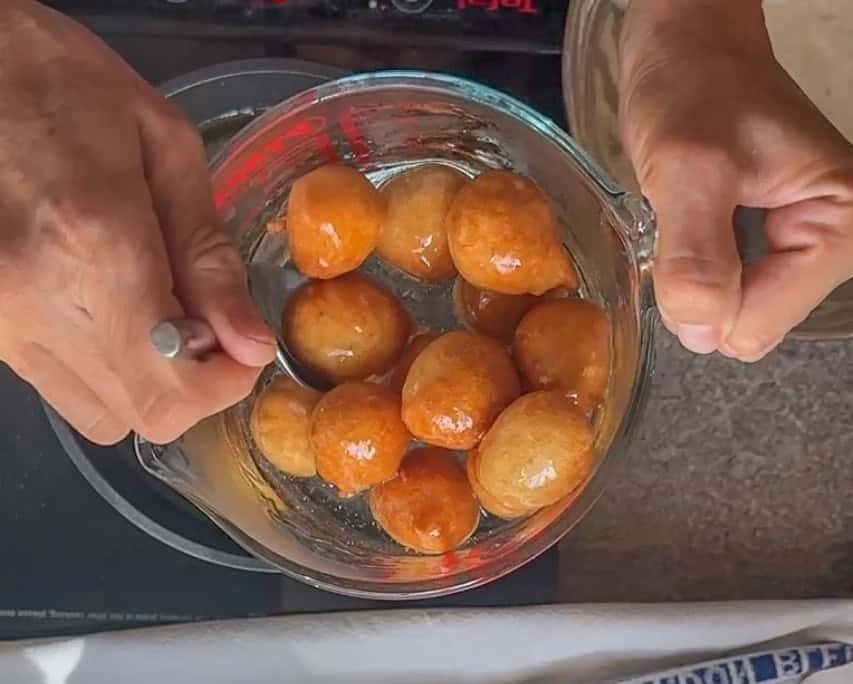 soaking fried lokma dessert balls in syrup
