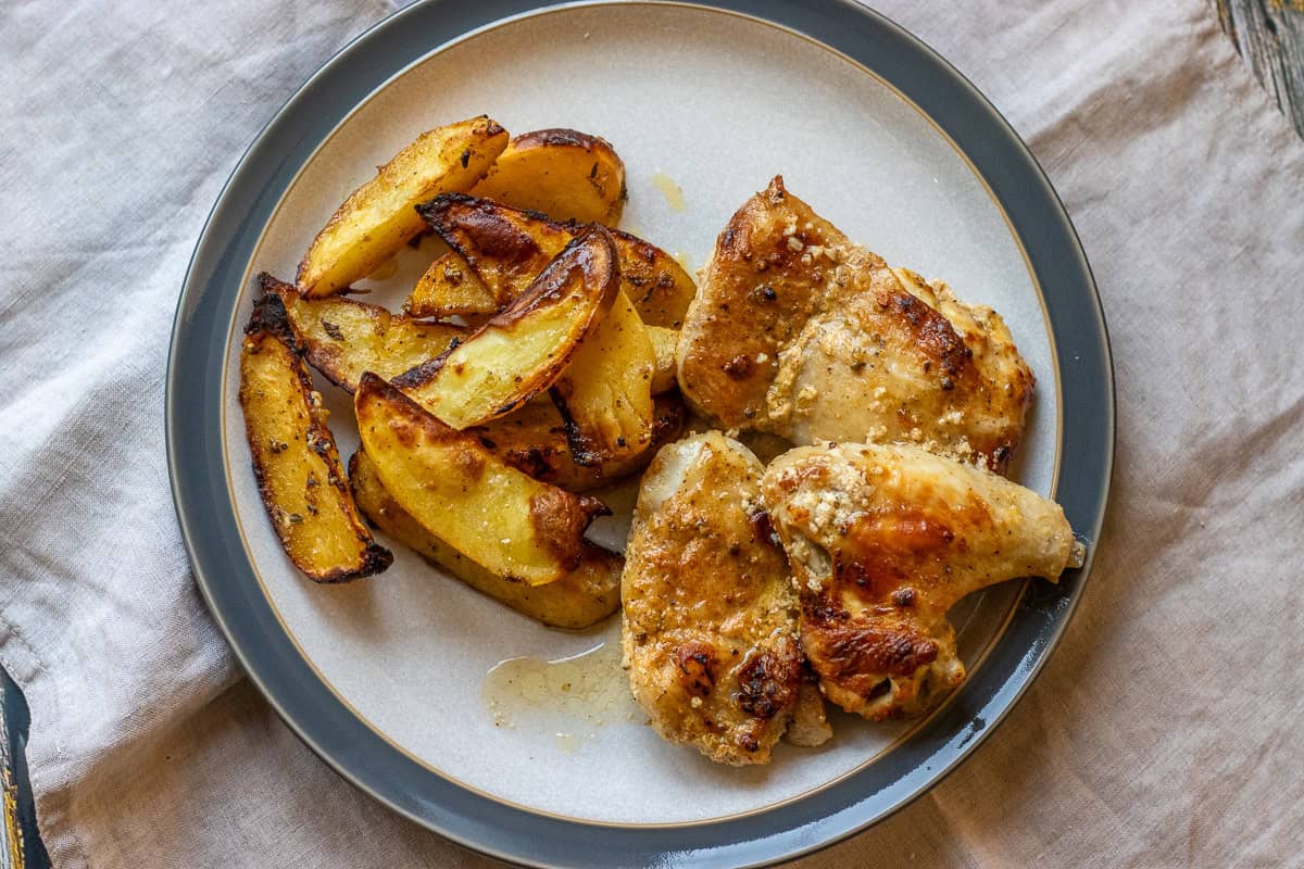 chicken pieces and potato wedges cooked with greek yogurt marinade served on a plate