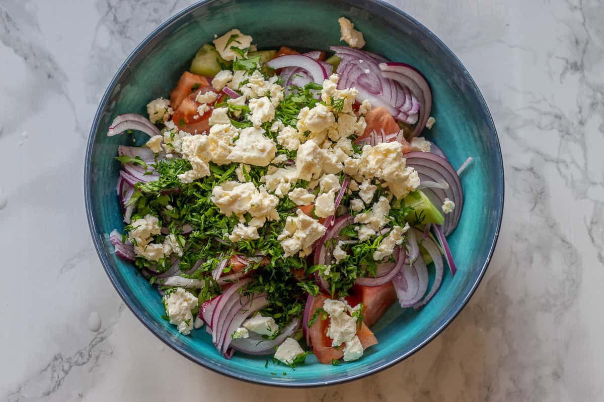 chopped veggies, and crubled feta are placed in a bowl