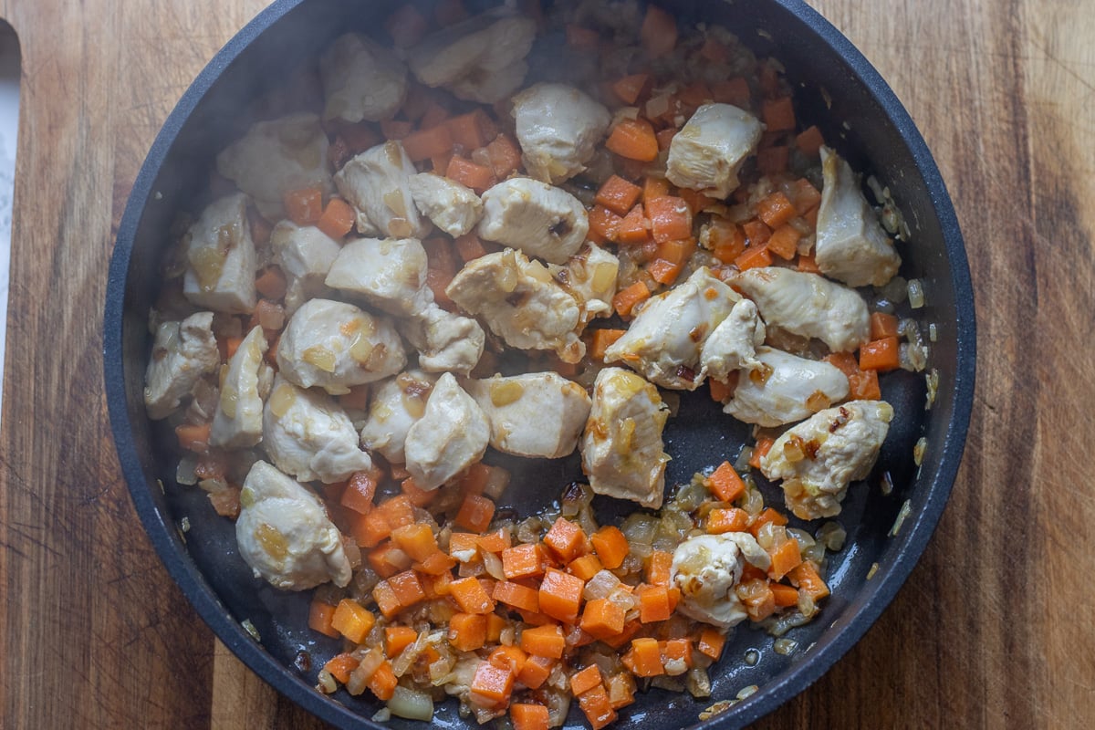 Chicken and carrots are added to sauteed onions.
