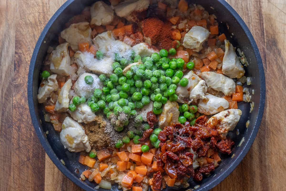 Peas, sun-dried tomatoes, and seasoning are added to the pot.