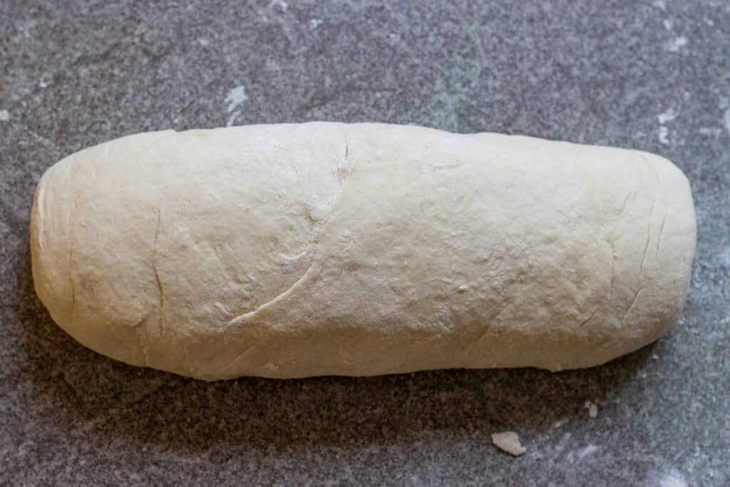 The rectangular dough is rolled into a log shape.