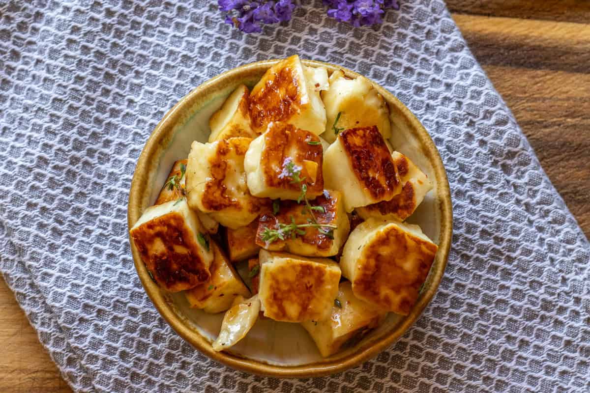 Fried halloumi pieces are served in a bowl.