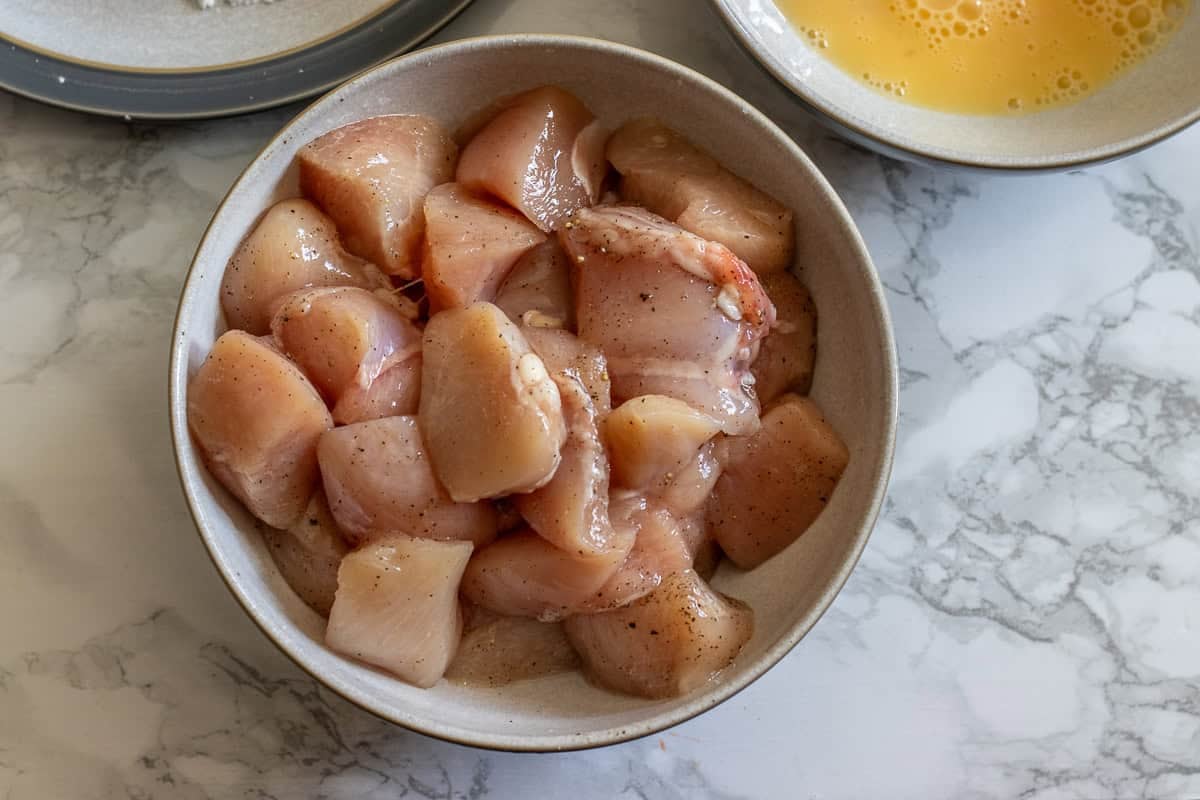 Chicken thighs are cut into cubes and seasoned with salt and pepper.