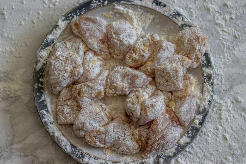 Chicken pieces are covered with cornstarch.