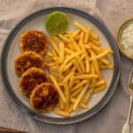 Overhead plate of salmon patties with french fries and half a lime.