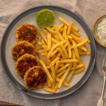Overhead plate of salmon patties with french fries and half a lime.