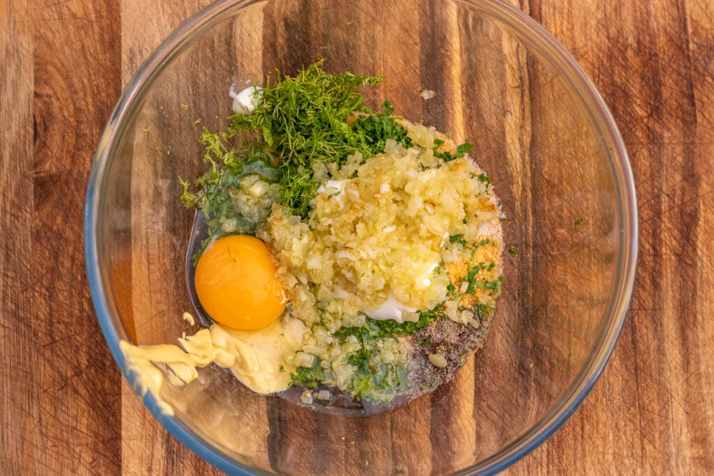 Breadcrumbs, parsley, lime zest, egg, mayonnaise, and Dijon mustard in a glass mixing bowl.