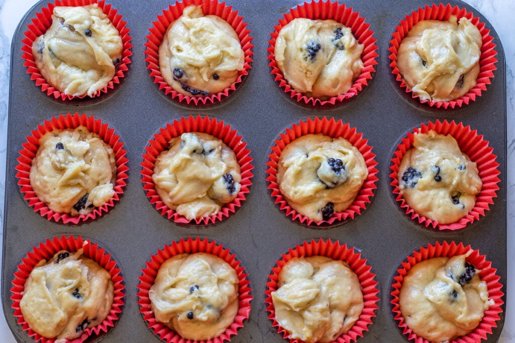 Muffin liners filled with batter and berries.