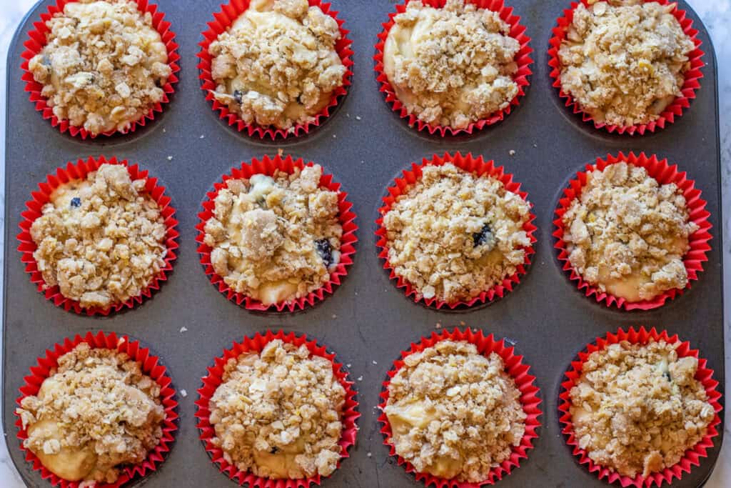 Streusel scattered over the unbaked muffins in the pan.